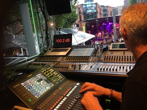 Een technicus bedient een mengpaneel tijdens een live muziekoptreden.
